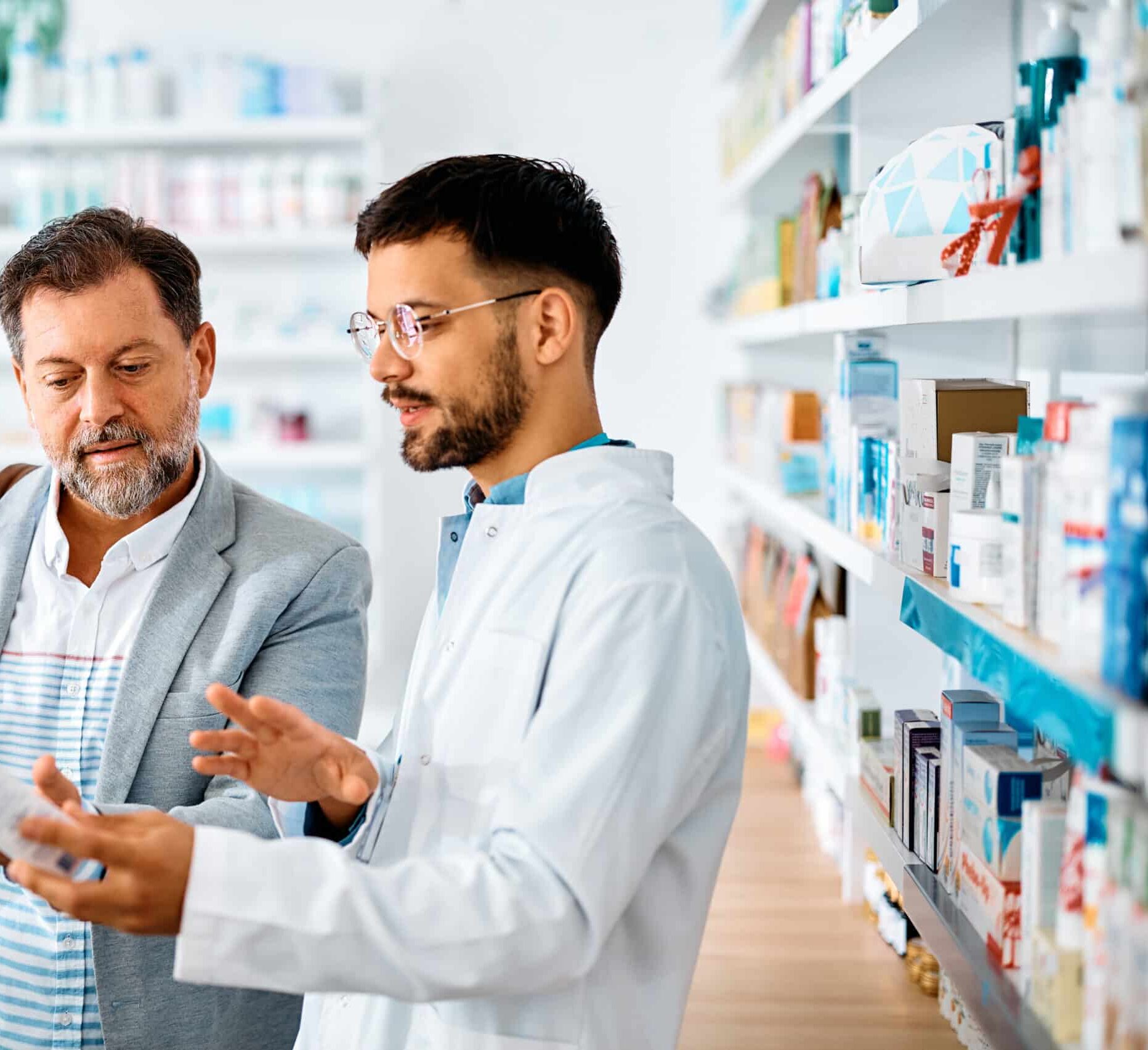 Middle aged man advising with his pharmacist about medicine in drugstore.